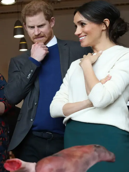 Ekspresi Pangeran Harry dan Meghan Markle saat melihat anggota tubuh buatan atau prostetik di Catalyst Inc, Belfast, Irlandia Utara, Jumat (23/3). Kunjungan keduanya ke Irlandia Utara bagian dari tur pranikah. (Niall Carson/Pool via AP)