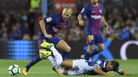 Gelandang Barcelona, Andres Iniesta, mengamankan bola dari tekel penyerang Espnayol, Daniel Piatti, pada laga La Liga Spanyol di Stadion Camp Nou, Katalonia, Sabtu (9/9/2017). Barcelona menang 5-0 atas Espanyol. (AFP/Lluis Gene)