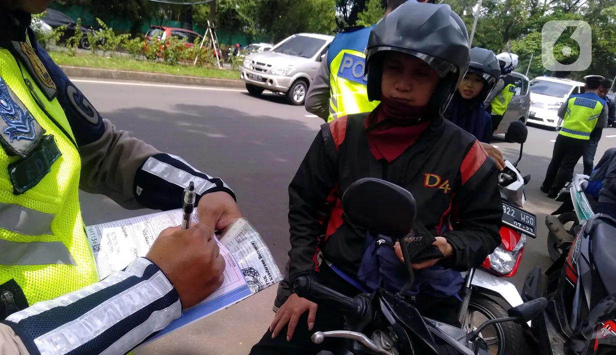 Polisi menilang pengendara sepeda motor saat razia di kawasan BSD, Tangerang Selatan, Banten, Kamis (23/1/2020). Polres Tangerang Selatan menggelar razia untuk meningkatkan tertib berlalu lintas, disiplin kendaraan, dan mempersempit gerak pelaku kejahatan jalanan. (merdeka.com/Arie Basuki)