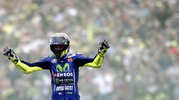 Pebalap Movistar Yamaha, Valentino Rossi, mengangkat tangan saat finish pertama pada MotoGP Belanda di Sirkuit Assen, Assen, Minggu (25/6/2017). Riders asal Italia itu memiliki catatan waktu 41 menit 41,149 detik. (AFP/Vincent Jannink) 