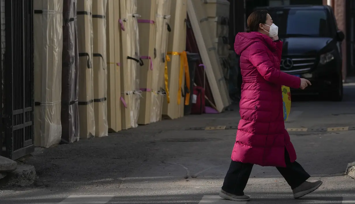 Seorang perempuan yang mengenakan masker berjalan di dekat peti mati kosong yang ditempatkan di kamar mayat sebuah rumah sakit di Beijing, Jumat (6/1/2023). China berupaya meminimalkan kemungkinan wabah COVID-19 yang lebih besar selama kesibukan perjalanan Tahun Baru Imlek bulan ini menyusul berakhirnya sebagian besar langkah-langkah pencegahan pandemi. (AP Photo/Andy Wong)