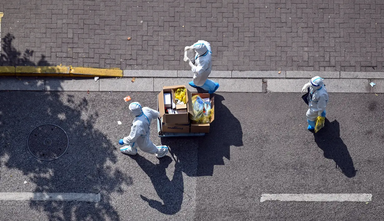 Petugas kesehatan yang mengenakan alat pelindung diri berjalan di jalan saat lockdown tahap kedua akibat COVID-19 di Distrik Jing'an, Shanghai, China, Rabu (6/4/2022). (Hector RETAMAL/AFP)