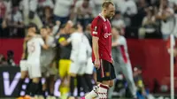 Pemain Manchester United, Christian Eriksen, tertunduk lesu kala para pemain Sevilla merayakan gol yang dicetak Youssef En-Nesyri, dalam pertandingan leg kedua perempat final Liga Europa di Ramon Sanchez Pizjuan, Jumat (21/4/2023) dini hari WIB. MU kalah 0-3 dalam laga ini dan tersingkir dari Liga Europa dengan skor agregat 2-5. (AP Photo/Jose Breton)