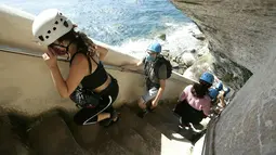 Turis menaiki tangga Raja Aragon di Bonifacio di pulau Corsica, Mediterania Prancis (19/9/2021). Pada kenyataannya, tangga itu digali oleh para biarawan Fransiskan untuk mengakses sumber air minum, yang tidak lagi digunakan. (AFP/Pascal Pochard-Casabianca)