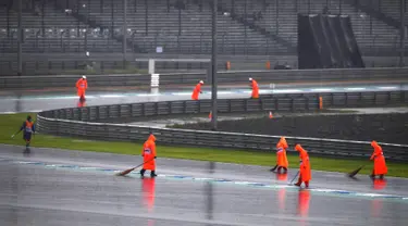 Pekerja menyapu air hujan ke luar lintasan saat sesi latihan dan kualifikasi kualifikasi MotoGP Thailand 2019 di Sirkuit Internasional Buriram, Sabtu (5/10/2019). Hujan deras mengakibatkan sesi latihan dan kualifikasi MotoGP Thailand 2019 ditunda. (Lillian SUWANRUMPHA/AFP)