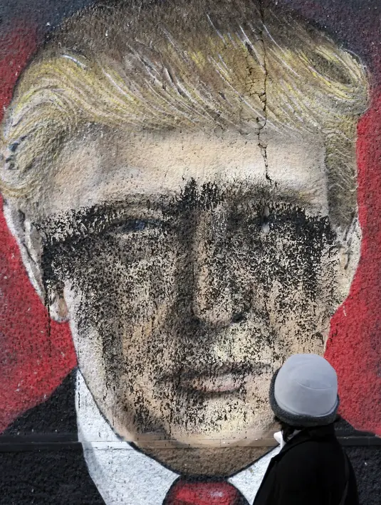 Seorang pria melihat grafiti bergambar Presiden AS terpilih Donald Trump yang dirusak dengan cat di Belgrade, Serbia, Jumat (20/1). Trump hari ini akan dilantik menjadi Presiden AS. (AP Photo / Darko Vojinovic) 