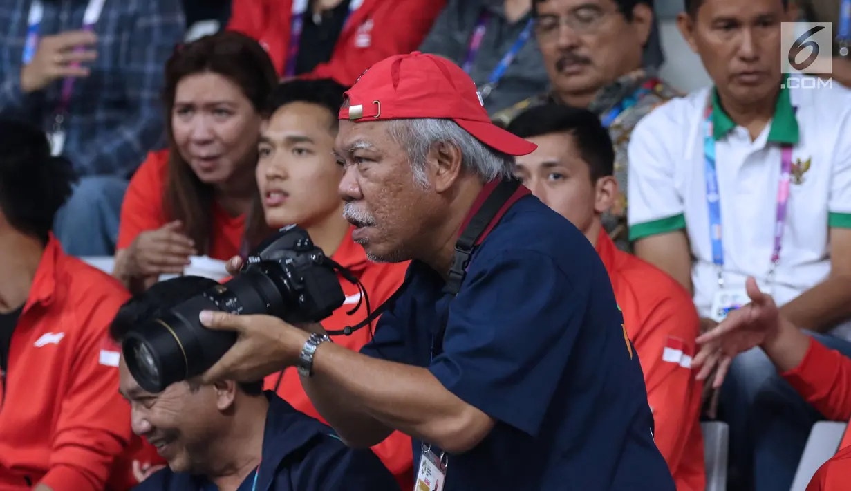 Menteri PUPR, Basuki Hadimuljonobersiap mengabadikan momen saat laga semifinal bulu tangkis beregu putra Asian Games 2018, Indonesia melawan Jepang di Jakarta, Selasa (21/8). Indonesia unggul dan lolos ke final. (Liputan6.com/Helmi Fithriansyah)