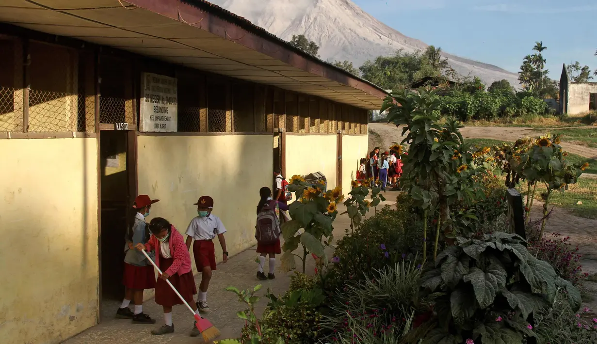 Murid menyapu saat Gunung Sinabung mengeluarkan abu vulkanik di sebuah sekolah dasar di Beganding, Sumatra Utara, (20/2). (AP Photo / Ahmad Putra)