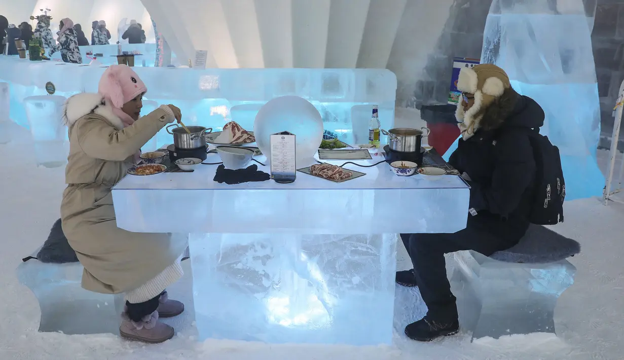 Foto yang diambil 13 Januari 2020 menunjukkan orang-orang menikmati hot pot di meja dan kursi berukir es di dalam igloo selama Festival Es dan Salju Internasional Harbin tahunan.  Restoran berbentuk rumah salju bangsa Eskimo ini hadir untuk memberikan sensasi makan malam yang berbeda. (STR/AFP)