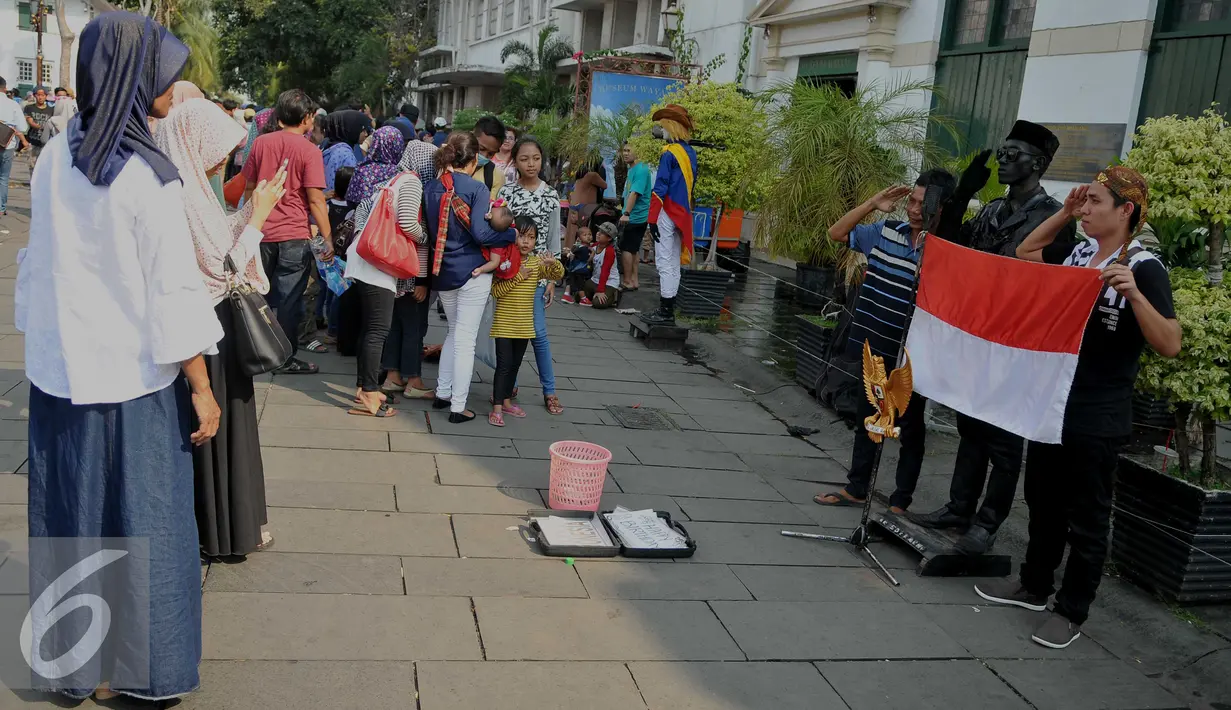 Pengunjung berpose dengan manusia patung saat mengunjungi Kota Tua, Jakarta, Jumat (8/7). Kota Tua menjadi salah satu pilihan masyarakat Jakarta ataupun luar Jakarta, untuk mengisi libur lebaran. (Liputan6.com/Gempur M Surya)