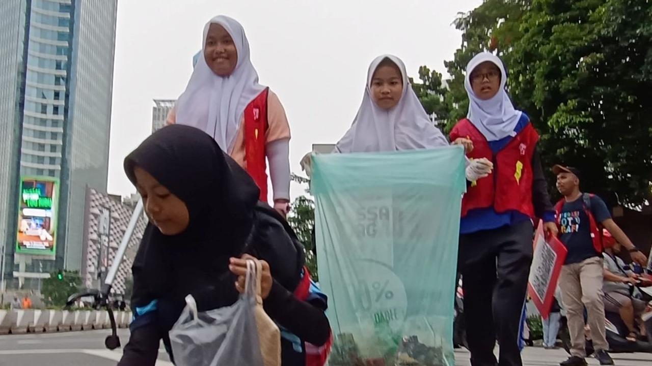 Anak-anak yatim-piatu memunguti sampah-sampah yang ditemukan saat hari bebas kendaraan bermotor (HBKB) atau car free day (CFD) di kawasan Thamrin, Jakarta, Minggu(25/2/2024). Foto: merdeka.com / Arie Basuki
