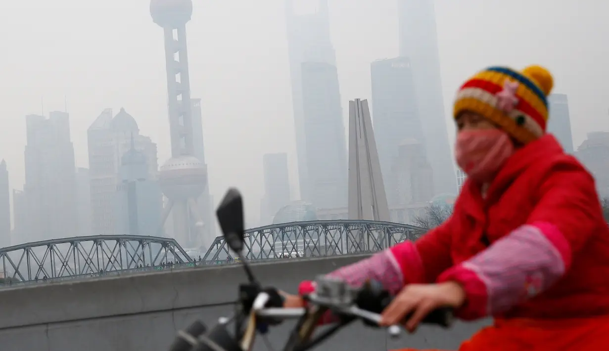 Warga mengenakan masker saat bersepeda melintasi jalanan Shanghai yang masih diselimuti kabut asap tebal, Cina, 2 Januari 2017. (REUTERS/Aly Song)