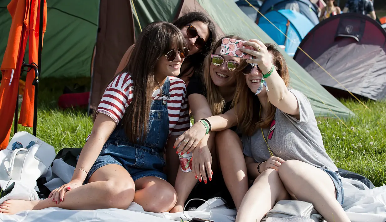 Dua wanita bersantai di tempat tidur gantung saat menghadiri Festival Musik Glastonbury di Worthy Farm, di Somerset, Inggris, (22/6). Festival Glastonbury merupakan festival musik paling populer di dunia. (AFP Photo/Oli Scarff)