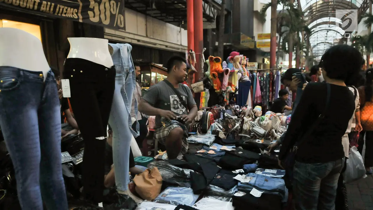 Pedagang melayani calon pembeli di kawasan perbelanjaan Pasar Baru, Jakarta Pusat