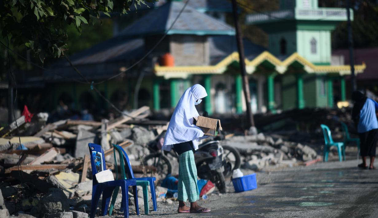 Seorang anak yang terkena dampak gempa meminta sumbangan pada pengguna jalan yang melintas di Donggala, Sulawesi Tengah, Jumat (5/10). Akibat terlambatnya pasokan bantuan, mereka terpaksa meminta sumbangan hingga turun ke jalan. (AFP PHOTO / Jewel SAMAD)