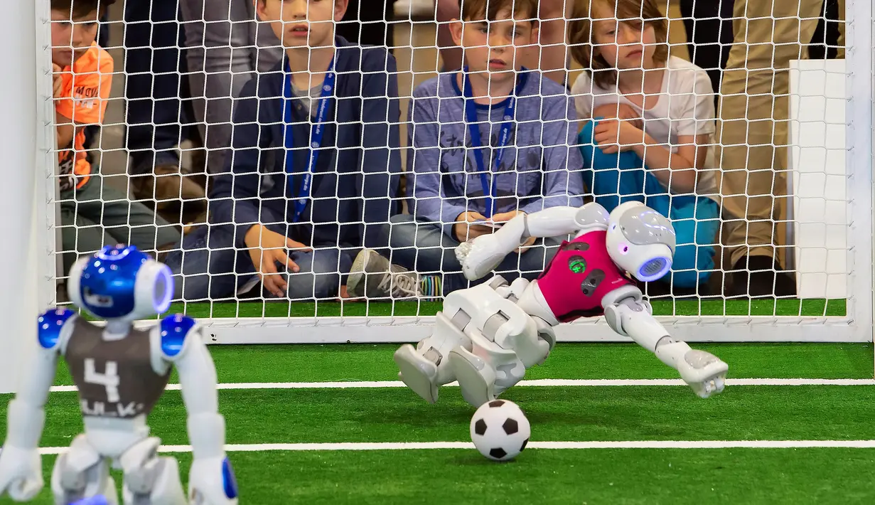 Robot penjaga gawang tim 'Nomadz' Swiss berhasil menahan bola saat melawan robot tim 'Hulk' dari Jerman dalam pertandingan kompetisi Liga Platform Standar di RoboCup GermanOpen 2018, Magdeburg, Jerman (28/4). (AP/Jens Meyer)