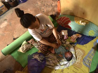 Armila merawat bayi laki-lakinya yang berusia sehari, Muhammad Al Aksa, di tempat pengungsian sementara setelah gempa berkekuatan 6,2 skala Richter mengguncang kota Mamuju, Sulawesi, Selasa (19/1/2021). (AFP/Firdaus)