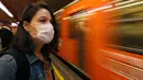 Seorang wanita mengenakan masker menunggu kereta di Mexico City (23/3/2020). Otoritas kota mengumumkan langkah-langkah untuk menangani virus corona baru seperti menutup bar, disko, museum, kebun binatang, bioskop, teater dan gym mulai Senin. (AP Photo/Marco Ugarte)
