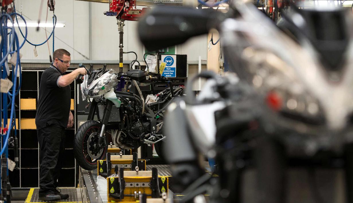 Pekerja mengencangkan baut bagian depan sepeda motor Triumph di pabriknya di Hinckley, Inggris (2/10). Pada tahun 1902 Triumph berkembang memproduksi sepeda motor pertama, Triumph 1. (AFP Photo/Oli Scarff)