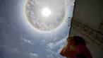 Seorang wanita mengamati fenomena Halo Matahari yang terjadi di atas langit kota Caracas, ibu kota Venezuela, 10 Mei 2016. Fenomena langka itu dinamakan Halo Matahari yang terbentuk akibat refleksi dari kristal es. (Juan BARRETO/AFP)