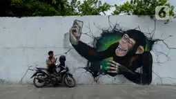 Pengendara berhenti dekat kreasi mural di sepanjang dinding bantaran Kali Opak, Jakarta Utara, Kamis (6/2/2020). Tembok bangunan saat ini tak hanya menjadi pembatas semata tapi dimanfaatkan untuk menyampaikan pesan-pesan dan harapan dalam bentuk goresan atau tulisan. (merdeka.com/Imam Buhori)