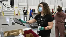 Pekerja di distributor McKesson Corporation memeriksa slip kemasan untuk vaksin Johnson & Johnson di fasilitas pengiriman mereka di Shepherdsville, Kentucky, Senin (1/3/2021). Vaksin Covid-19 Johnson & Johnson menjadi vaksin corona ketiga yang sah digunakan di AS. (AP Photo/Timothy D. Easley, Pool)