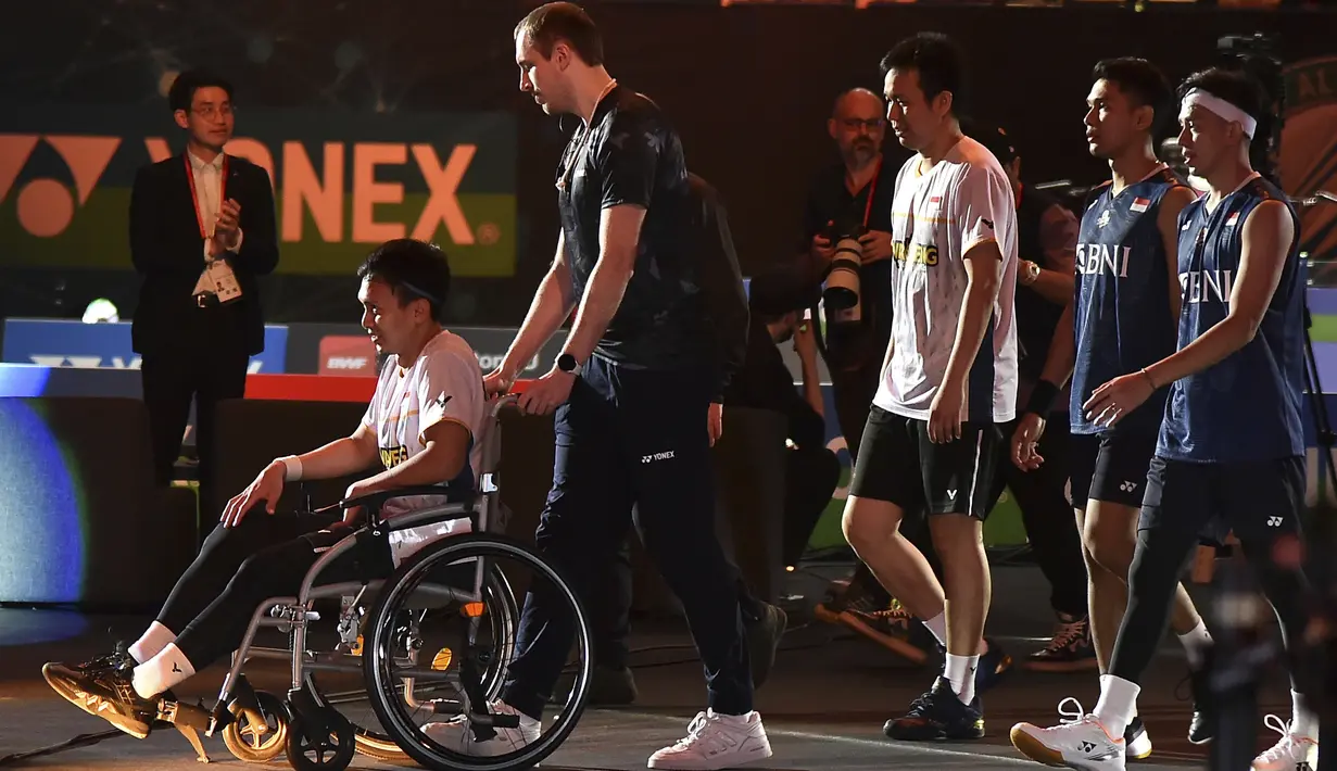 Mohammad Ahsan (kiri) dibantu kursi roda diikuti pasangannya Hendra Setiawan (tengah) serta pemenang ganda putra All England 2023, Fajar Alfian/Muhammad Rian Ardianto menuju podium saat mengikuti prosesi penerimaan medali. (AP Photo/Rui Vieira)