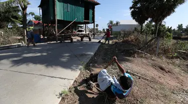 Seorang pria menarik rumah kayu ke tempat di desa Pon Sang di sisi utara Phnom Penh, Kamboja (26/4/2020). Ini adalah cara bergerak tradisional yang dikumpulkan oleh penduduk desa untuk saling membantu dengan menggunakan traktor dan batang kayu. dengan menjaga rumah tetap utuh. (AP/Heng Sinith)