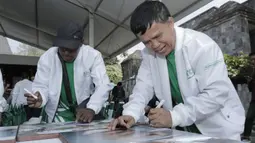 Legenda tinju Indonesia, Ellyas Pical, menandatangani foto saat pameran foto di Yogyakarta, Rabu (18/7/2018). Pameran foto legenda olahraga Indonesia tersebut sekaligus peluncuran kampanye Grab "Kemenangan itu Dekat". (Bola.com/M Iqbal Ichsan)