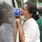 Seorang wanita bereaksi ketika petugas kesehatan mengambil sampel usap hidung darinya saat tes publik untuk virus corona COVID-19 yang dilakukan di stasiun kereta api di Bekasi, Jawa Barat, Rabu (2/2/2022). (AP Photo/Achmad Ibrahim)