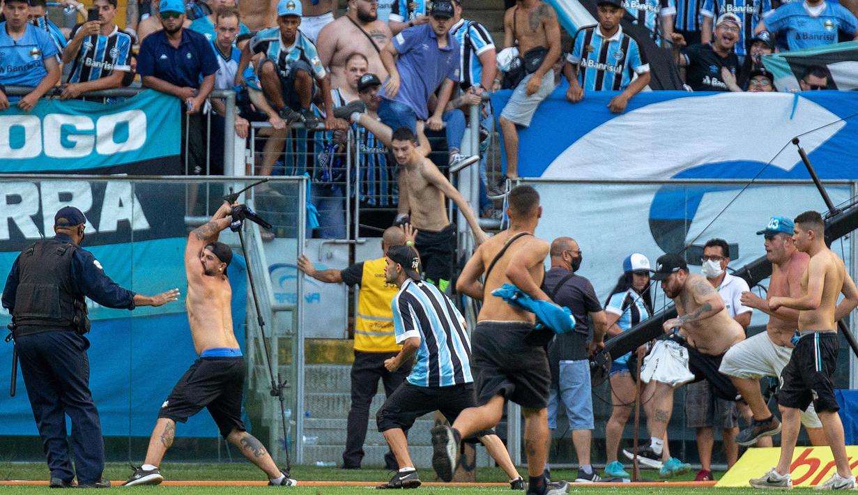 Selain itu para suporter yang mengamuk itu juga tanpa ragu menyerang petugas keamanan yang berjaga di lapangan. Mereka melempari petugas dengan botol dan batu. Aksi baku hantam pun tidak dapat dihindari. (AFP/Raul Pereira)
