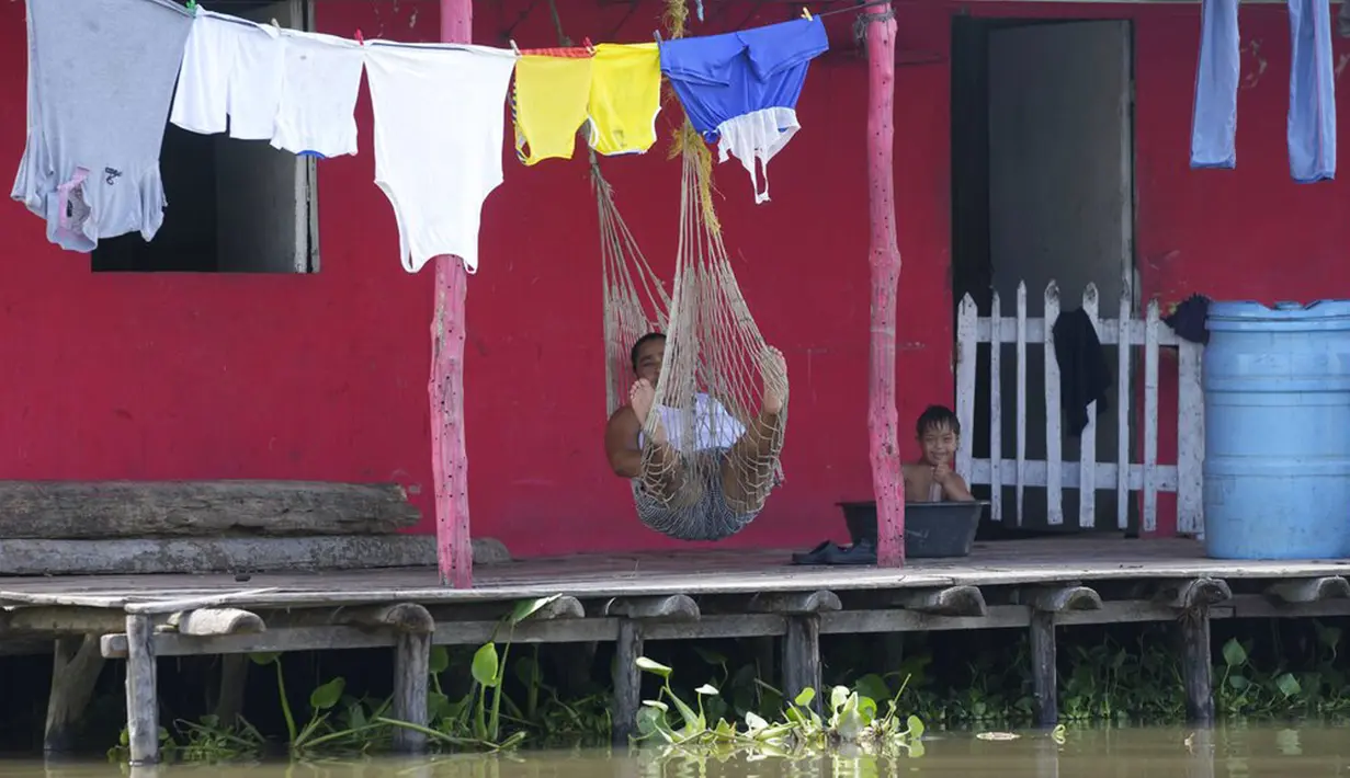 Seorang wanita beristirahat di tempat tidur gantung di teras rumahnya di Cienaga Grande de Santa Marta, Nueva Venecia, Kolombia, 12 Oktober 2021. Cienaga Grande merupakan rawa terbesar di Kolombia antara Sungai Magdalena dan pegunungan Sierra Nevada de Santa Marta. (AP Photo/Fernando Vergara)