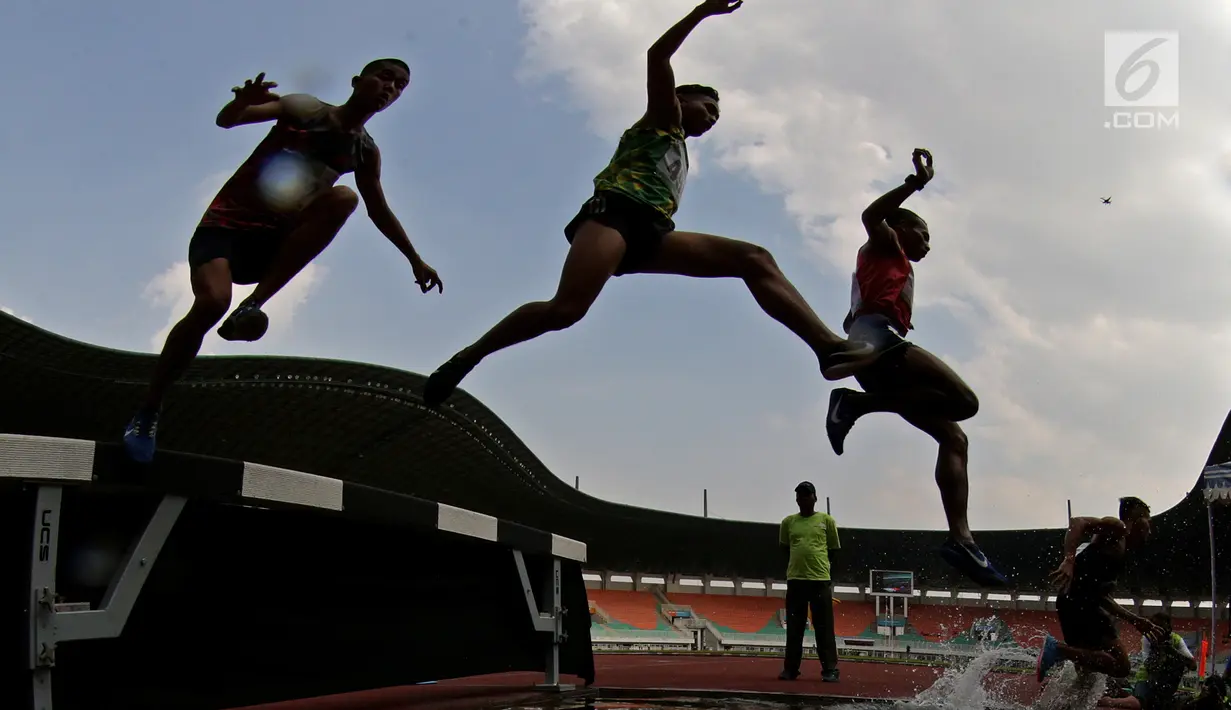 Para pelari melompat saat tampil pada Kejurnas Atletik 2019 nomor 3.000 meter steeplechase senior putra di Stadion Pakansari, Bogor pada Rabu (8/8/2019). Kejurnas Atletik berlangsung dari 3 hingga 7 Agustus. (Bola.com/Peksi Cahyo)