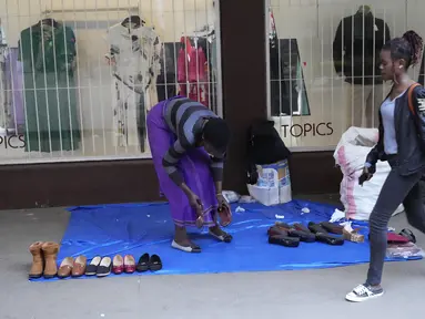 Pedagang kaki lima memajang sepatu baru dan bekas dengan harga murah di luar pintu masuk toko pakaian di jalanan Harare, dalam foto Senin, 22 Mei 2023 ini. (AP Photo/Tsvangirayi Mukwazhi)