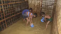 Anak-anak pengungsi Rohingya mengeluarkan air banjir dari rumah mereka di kamp pengungsi Rohingya di Kutupalong, Bangladesh (28/7/2021). Ribuan pengungsi kehilangan tempat tinggal akibat banjir tersebut. (AP Photo/Syafiqur Rahman)