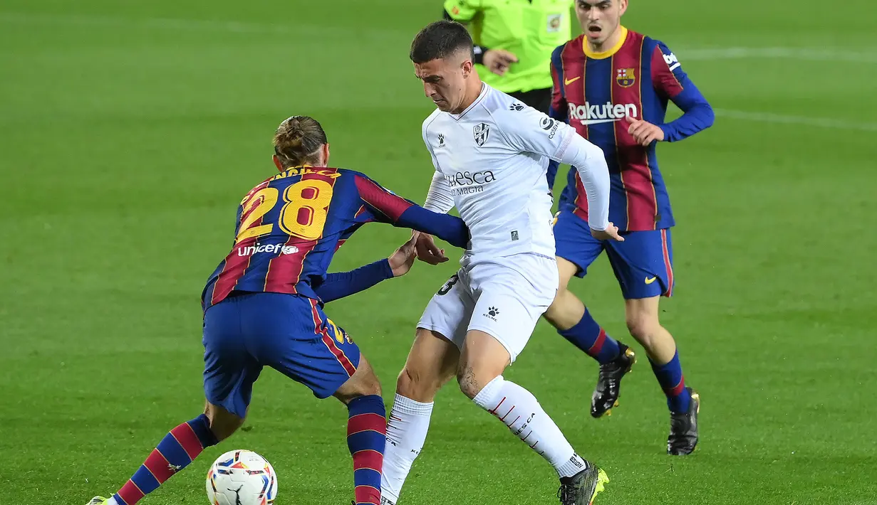 Bek SD Huesca, Pablo Maffeo (tengah) mencoba melewati hadangan bek Barcelona, Oscar Mingueza dalam laga lanjutan Liga Spanyol 2020/2021 pekan ke-27 di Camp Nou Stadium, Barcelona, Senin (15/3/2021). SD Huesca kalah 1-4 dari Barcelona. (AFP/Lluis Gene)