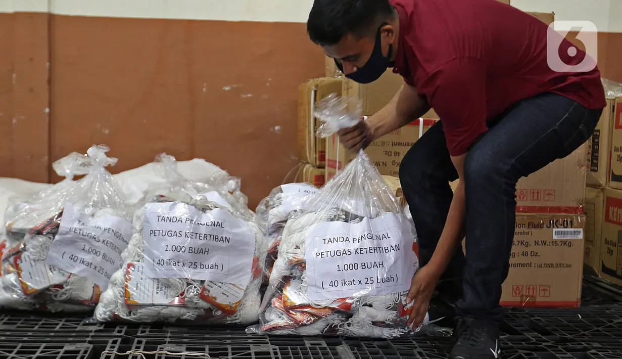 Petugas menata tanda pengenal petugas ketertiban di Gudang Logistik KPU, Depok, Jawa Barat, Jumat (13/11/2020). KPU Kota Depok telah merakit 4.015 kotak suara serta menyediakan 16.060 bilik suara yang akan digunakan untuk Pilkada Kota Depok pada 9 Desember 2020. (Liputan6.com/Herman Zakharia)