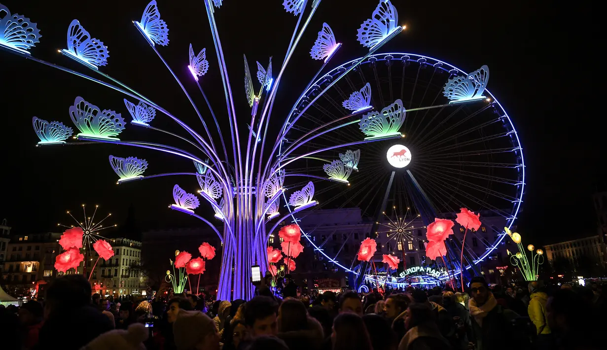 Orang-orang melihat sebuah instalasi seni yang diterangi cahaya dalam festival cahaya tahunan bernama Fete des Lumieres di Lyon, Prancis, 7 Desember 2017. Festival ini berlangsung bertepatan dengan musim liburan Natal. (AFP PHOTO / PHILIPPE DESMAZES)
