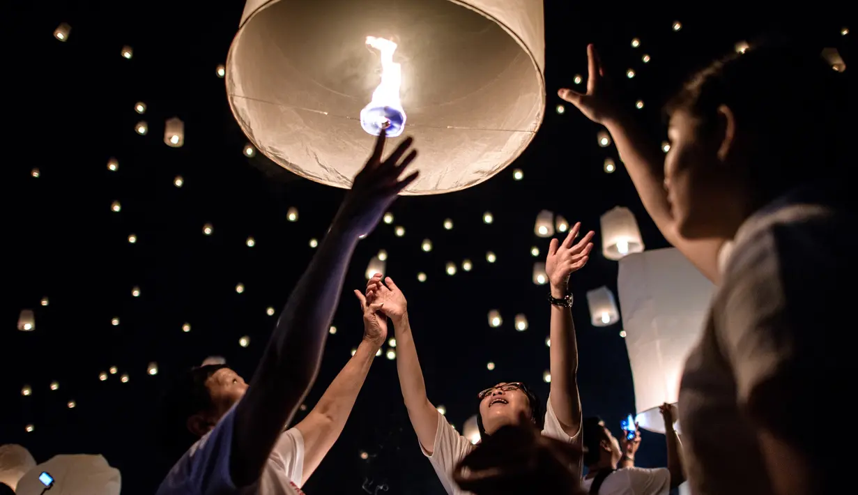 Warga melepaskan lampion ke udara saat perayaan festival Yee Peng di Chiang Mai (3/11). Dalam festival ini, ratusan bahkan ribuan orang beramai-ramai menerbangkan lampion. (AFP Photo/Roberto Schmidt)