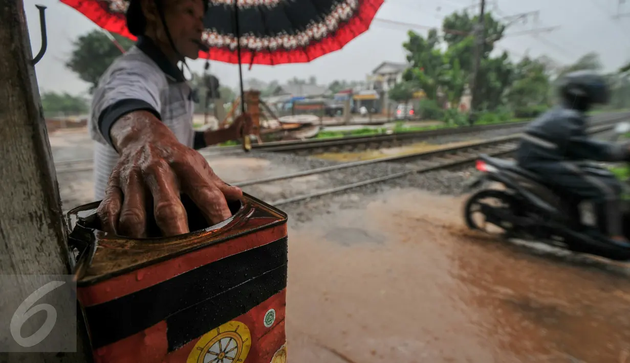 Muhamad Ali menjaga perlintasan kereta di Pondok Cina. Ali menyambung hidupnya dari para pengendara yang memberinya secara sukarela saat melintas di perlintasan kereta Pondok Cina, Depok, Minggu (13/12/2015). (Liputan6.com/Yoppy Renato)