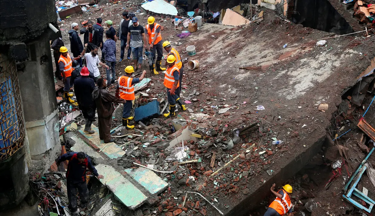 Petugas penyelamat berkumpul di lokasi ambruknya bangunan perumahan di pinggiran Mumbai, India, Minggu (31/7). Sebuah bangunan perumahan ambruk akibat hujan lebat dan menewaskan sembilan orang termasuk empat anak-anak. (REUTERS/Shailesh Andrade)