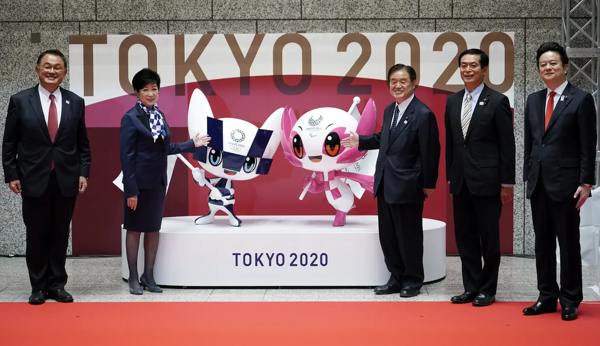 Penyelenggara berpose dengan Miraitowa dan Someity, maskot untuk Olimpiade dan Paralimpiade Tokyo 2020/2021, saat menandai 100 hari sebelum dimulainya Olimpiade di gedung Pemerintah Metropolitan Tokyo, Rabu (14/4/2021). Olimpiade Tokyo akan dibuka pada 23 Juli 2021. (AP Photo/Eugene Hoshiko, Pool)