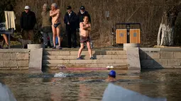 Sejumlah pria bersiap berenang di sungai yang sebagian membeku di Beijing, China (10/1). Akibat membeku, Sungai ini menjadi objek wisata dadakan. (AFP Photo/Wang Zhao)