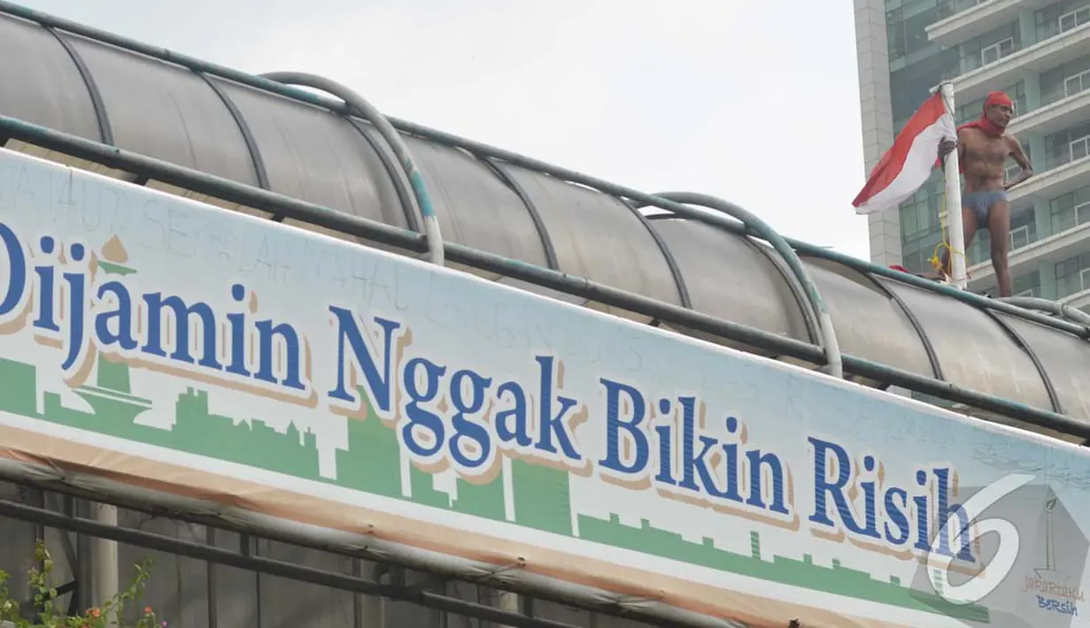 Aksi Agustinus semakin aneh, Ia membuka pakaian luarnya. Aksinya ini menjadi perhatian orang-orang di sekitar Bundaran HI, Jakarta, Rabu (23/07/2014) (Liputan6.com/Johan Tallo)
