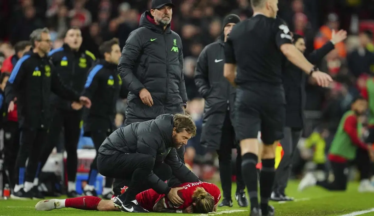Pemain Liverpool, Kostas Tsimikas, terkapar setelah berduel dengan pemain Arsenal, Bukayo Saka pada laga pekan ke-18 Premier League 2023/2024 di Stadion Anfield, Minggu (24/12/2023). (AP Photo/Jon Super)