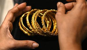 Gambar diambil pada 11 Agustus 2021 menunjukkan seorang pelanggan memegang gelang emas di sebuah toko perhiasan di Mumbai, India. Putus asa mendapatkan uang tunai, banyak keluarga dan usaha kecil menjual perhiasan emas sebagai jaminan untuk mendapatkan pinjaman jangka pendek. (Punit PARANJPE/AFP)