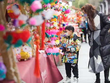 Orang-orang berbelanja lentera menjelang Festival Lampion, yang jatuh pada 15 Februari tahun ini - hari ke-15 Tahun Baru Imlek - di Nanjing di provinsi Jiangsu timur China pada 10 Februari 2022. Festival Lampion merupakan puncak sekaligus penutup dari perayaan Tahun Baru Imlek. (STR / AFP)