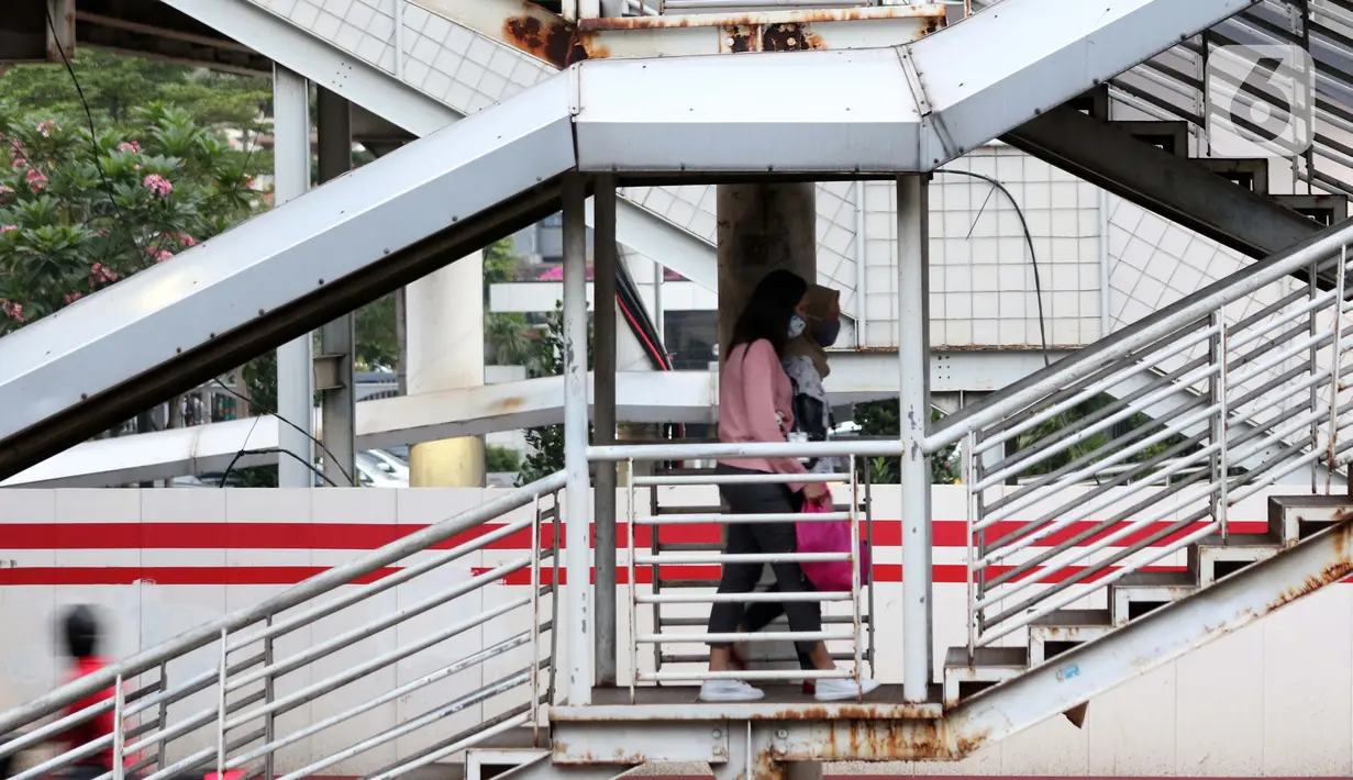 Warga berjalan di salah satu JPO di kawasan Jalan HR Rasuna Said, Jakarta, Rabu (8/7/2020). Wabah Covid-19 memengaruhi kondisi kesejahteraan masyarakat dan pertumbuhan ekonomi Indonesia pada tahun 2020 yang diproyeksikan -0,4 sampai dengan 1,0 persen. (Liputan6.com/Helmi Fithriansyah)