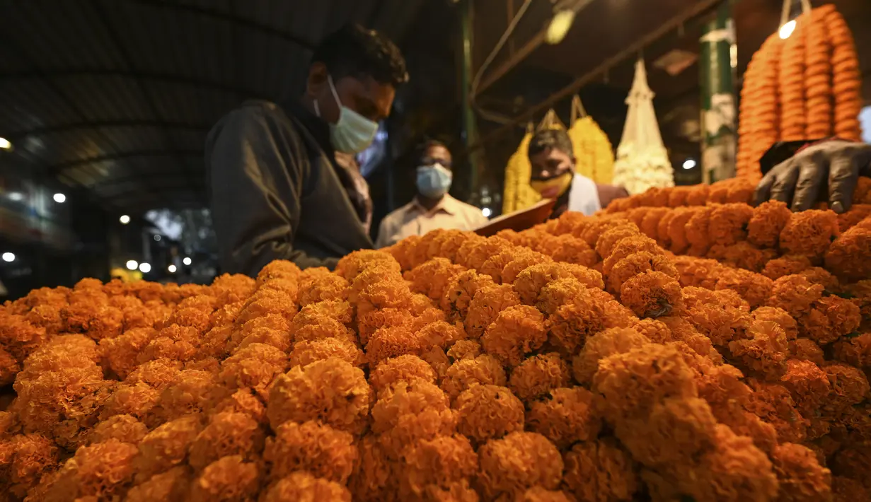 Karangan bunga dipajang pada sebuah toko jelang Festival Diwali di pasar bunga New Delhi, India, Minggu (31/10/2021). Festival Diwali atau Festival Cahaya dalam agama Hindu melambangkan kemenangan baik atas buruk. (Money SHARMA/AFP)
