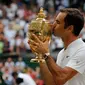 Petenis Swiss, Roger Federer mencium trofi setelah melawan petenis Kroasia, Marin Cilic pada pertandingan final tunggal putra Kejuaraan Wimbledon 2017 di Wimbledon, London. (16/07). Roger Federer menang 6-3, 6-1, 6-4. (AFP Photo / Adrian Dennis)